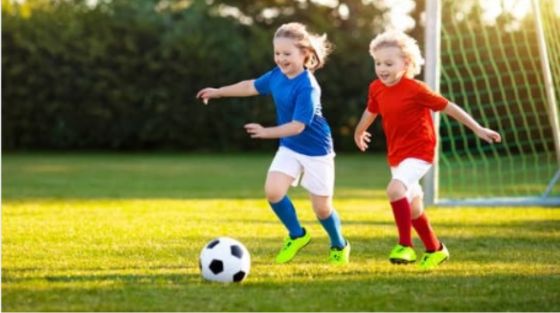 Two children happily playing soccer on a lush green field, highlighting their teamwork and excitement in the game.