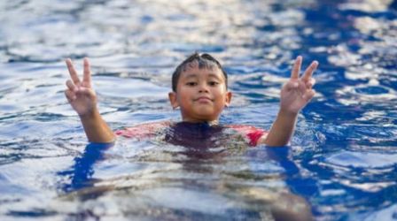 A boy joyfully raises his hands while playing in a pool, capturing a moment of fun and excitement during summer at Elan Presidential Phase 2 amenities.